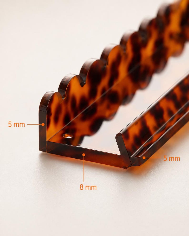 Pode incluir: Uma presilha de cabelo em acr&iacute;lico com padr&atilde;o de tartaruga e borda ondulada. A presilha tem formato de L, com espessura de 5 mm e largura de 8 mm. Projetada para manter o cabelo no lugar.