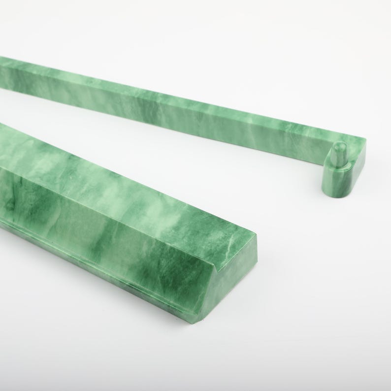 May include: Two jade green, rectangular, decorative bars with a marbled appearance. One bar has a small, cylindrical extension on the end. The bars are set against a white background. The bars appear to be made of stone.