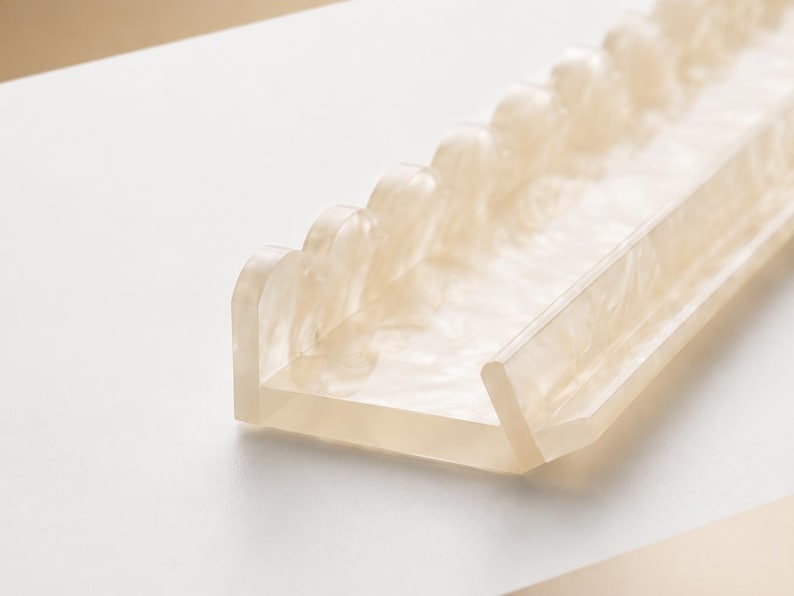 May include: A translucent, rectangular tray with a scalloped edge. The tray is made of a light beige material with a marbled effect. The design is modern and minimalist, suitable for organizing small items.