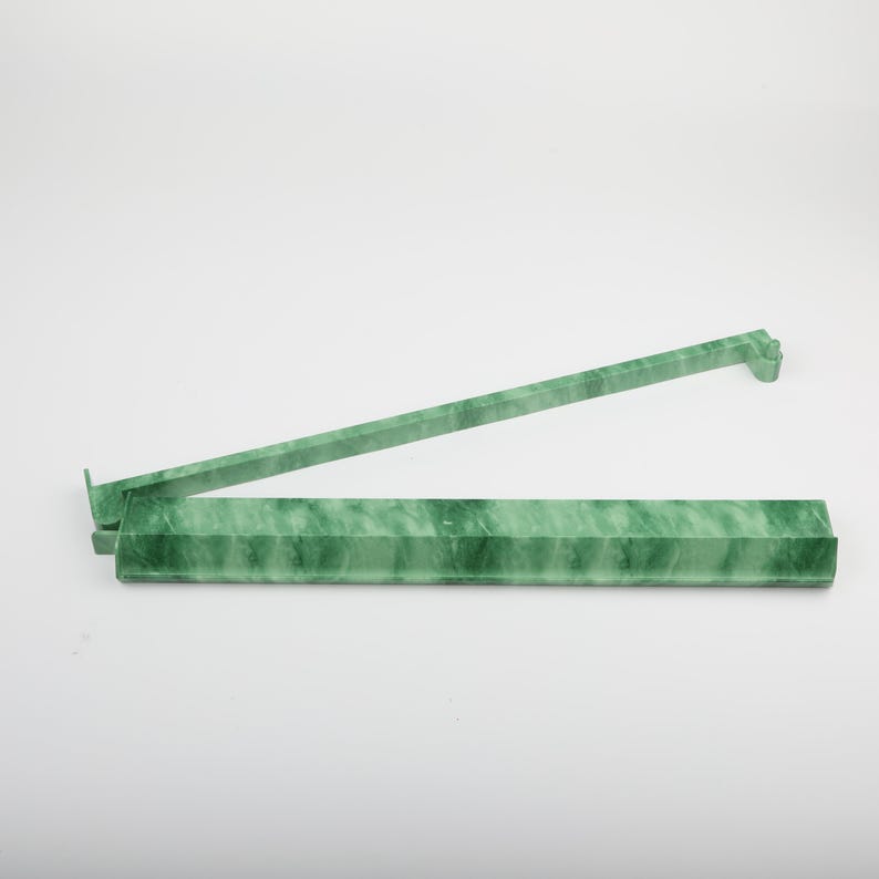 May include: A green, marble-patterned plastic ruler with a hinged design. The ruler is open, showing two connected sections. The color is a marbled green, with a light background.