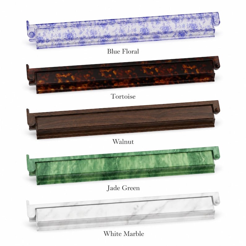 May include: A collection of five decorative trays in various styles. The trays include a blue floral design, tortoise shell, walnut, jade green, and white marble. Each tray has a rectangular shape with a raised edge and a small handle on each end.
