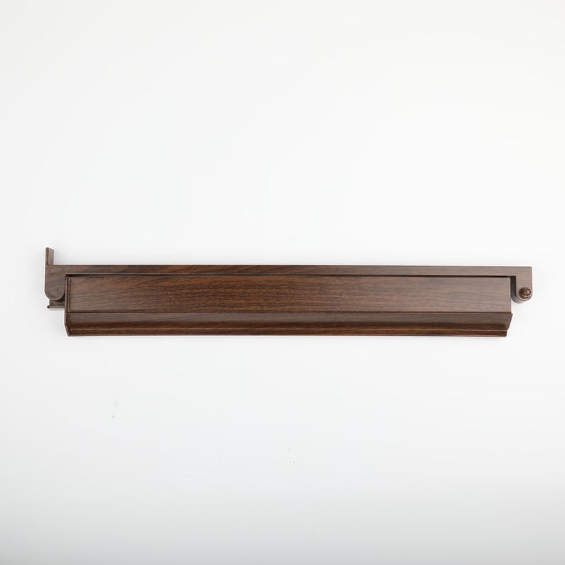 K&ouml;nnte beinhalten: Ein dunkelbraunes Holzregal mit rechteckigem Design. Das Regal hat eine erh&ouml;hte Vorderkante und ein dekoratives Endst&uuml;ck. Die Holzmaserung ist sichtbar und das Regal scheint neu zu sein.