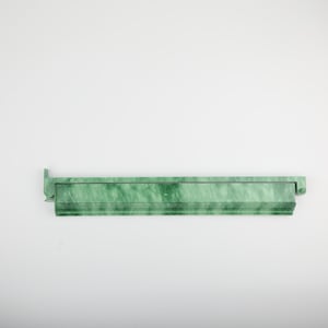 May include: A long, rectangular, green marble-look shelf with a decorative edge and a small, raised end piece. The shelf has a marbled pattern of light and dark green.