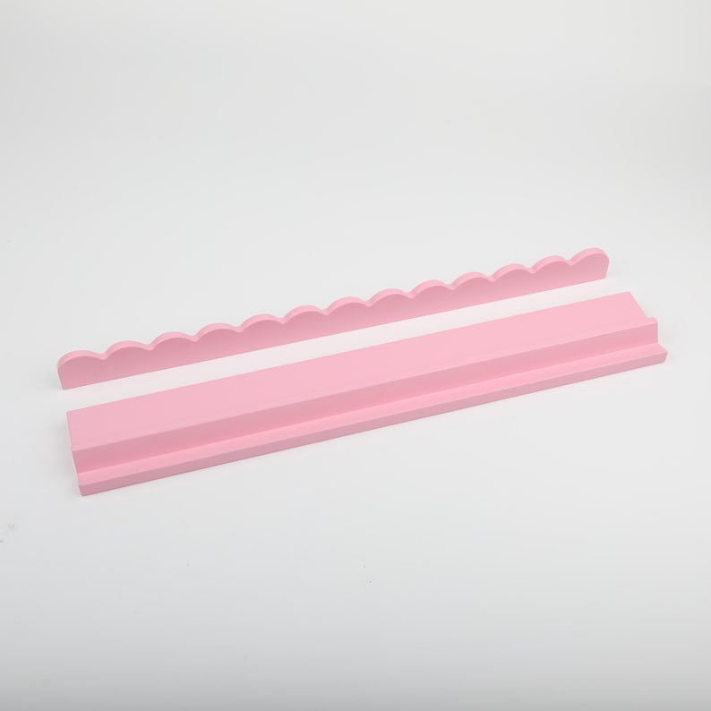 Puede incluir: Juego de estantes de madera rosa de dos piezas. El juego incluye una pieza con borde festoneado y un estante rectangular con un borde frontal elevado. Las piezas est&aacute;n pintadas de un color rosa suave y s&oacute;lido y est&aacute;n dise&ntilde;adas para montarse en la pared.