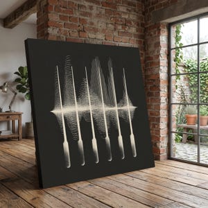 Op de afbeelding: Een groot, vierkant canvas kunstwerk met een zwarte achtergrond. Het kunstwerk toont een reeks verticale, crèmekleurige lijnen die lijken op geluidsgolven of abstracte vormen. Het stuk wordt tentoongesteld in een kamer met een bakstenen muur en houten vloer.