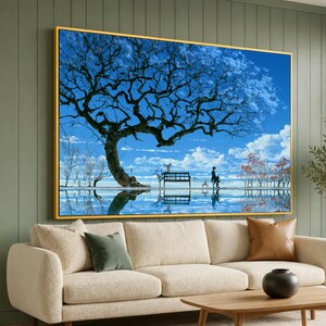 May include: A rectangular wall art piece in a gold frame featuring a landscape painting of a large, dark, leafless tree against a bright blue sky with white clouds. A small bench sits beneath the tree, with a figure nearby and water reflection.