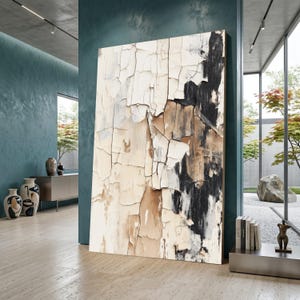 Könnte beinhalten: Großes abstraktes Kunstwerk mit strukturierter Oberfläche. Das Kunstwerk zeigt eine Palette aus Off-White, Beige, Braun und Schwarz, wodurch ein verwitterter, abblätternder Farbeffekt entsteht. Präsentiert in einem modernen Innenraum.