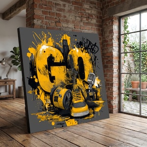 以下が含まれることがあります： 「GO」の文字が大きく黄色で描かれたキャンバスプリント。黒いアクセントとグラフィティ風の要素が特徴です。マイク、スニーカー、缶が同様の色使いで描かれています。背景は濃いグレーです。