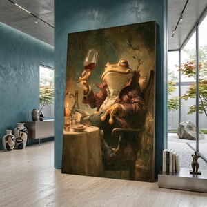 May include: A large canvas print depicts a frog in a burgundy jacket, seated at a table, raising a glass of red wine. The frog is the focal point, with a candle and wine bottle on the table. The artwork has a vintage, painterly style.