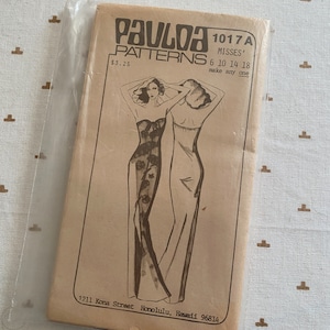 May include: A vintage sewing pattern envelope for a dress, featuring a line drawing of two women wearing long dresses. The pattern is called "Pauloa Patterns" and the number is 1017A. The envelope is brown and has a price tag of $3.25. The text on the envelope reads "Misses' 6 10 14 18 make any one".