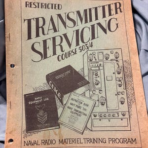 May include: A vintage manual titled "Transmitter Servicing Course 503/4" with the word "Restricted" at the top. The cover is tan with black text and illustrations of radio equipment and books. The manual is part of the Naval Radio Materiel Training Program.