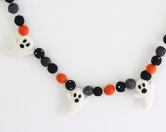 May include: A white felt ghost garland with black and orange felt balls. The garland is strung on a white thread and is perfect for Halloween decorations.