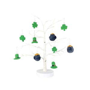Könnte beinhalten: Ein weißer Dekorationsbaum mit Filz-Anhängern. Die Anhänger sind grüne Kleeblätter, schwarze Goldtöpfe und grüne Koboldhüte.