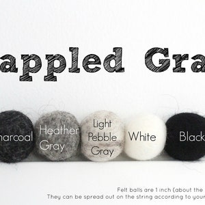 Peut inclure: Cinq boules de feutre dans diff&eacute;rentes nuances de gris, blanc et noir. Les boules sont &eacute;tiquet&eacute;es "Charcoal", "Heather Gray", "Light Pebble Gray", "White", et "Black". Le texte "Dappled Gray" est en haut de l'image. Les boules de feutre mesurent 2,5 cm (environ la taille d'une pi&egrave;ce de 25 cents).
