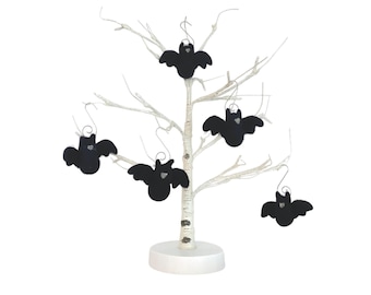 May include: A set of five black felt bat ornaments hanging from a white birch tree branch. The bats are all the same size and shape, and they have a simple, elegant design.