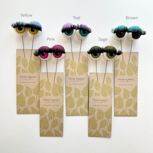 Peut inclure: Six marque-plantes en forme d'yeux en feutre de diff&eacute;rentes couleurs&nbsp;: jaune, rose, sarcelle, sauge, marron et vert. Chaque marque-plante a une paire d'yeux en feutre avec des cils et une tige en fil de fer noir. Les marque-plantes sont &eacute;tiquet&eacute;s "Planter Eyeballs".