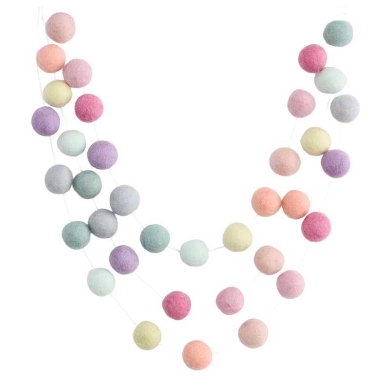 May include: A pastel colored felt ball garland with a variety of colors including pink, purple, blue, and green. The garland is strung on a white string and is perfect for adding a touch of whimsy to any room.