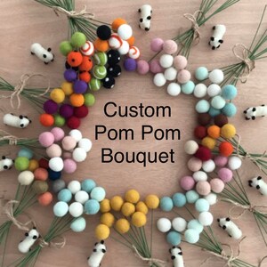 May include: A colorful assortment of felt pom poms arranged in a circle, with each pom pom attached to a green stem. The pom poms are in various colors, including red, orange, yellow, green, blue, purple, pink, and white. The text "Custom Pom Pom Bouquet" is written in the center of the circle.