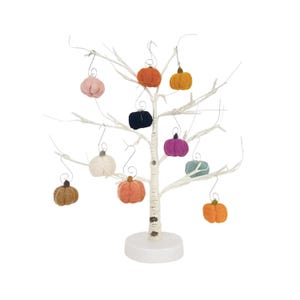 Puede incluir: Un árbol de abedul blanco con una base blanca, decorado con adornos de calabaza de fieltro en varios colores, incluyendo naranja, rosa, azul verdoso, negro y blanco.