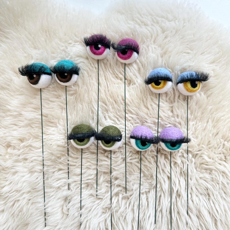Peut inclure: Neuf paires d'yeux en feutre avec des cils sur des tiges de fil. Les yeux sont de diff&eacute;rentes couleurs, notamment le vert, le bleu, le violet, le rose, le marron et le jaune.