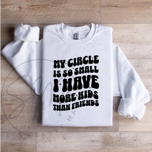 May include: White sweatshirt with black text that reads "My circle is so small I have more kids than friends".