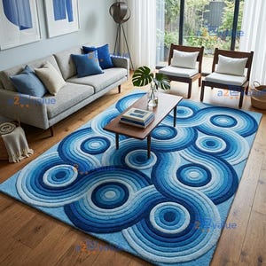 May include: A rectangular area rug featuring a textured, concentric circular pattern in various shades of blue, ranging from light sky blue to deep navy. The rug has a raised, tufted surface design that creates a ripple effect across the floor.