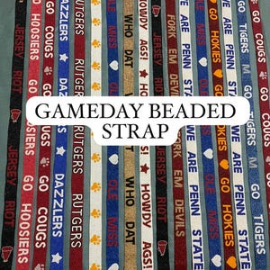 May include: A collection of beaded lanyards in various colors, featuring team names and phrases like "Go Cougars" and "We Are Penn State." Each strap has a metal clasp. The text "GAMEDAY BEADED STRAP" is displayed.
