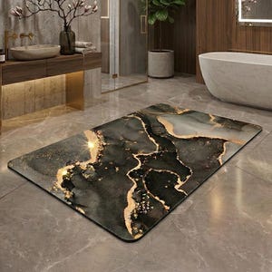 Op de afbeelding: Een rechthoekige badmat met een zwart, grijs en goud marmerontwerp. De mat ligt op een grijze tegelvloer in een moderne badkamer. De badkamer heeft een bad, een wastafel en een grote spiegel.