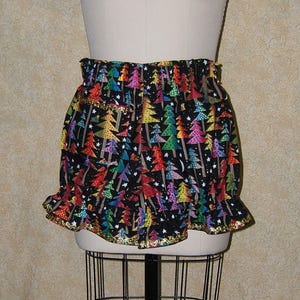 May include: Black and gold bubble shorts with a colorful Christmas tree print. The shorts have a ruffled hem and a gold elastic waistband.