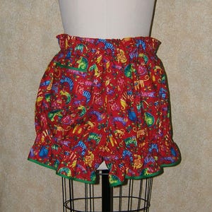 May include: Red, green, and blue patterned bloomers with a ruffled hem. The pattern features a variety of colorful animals.