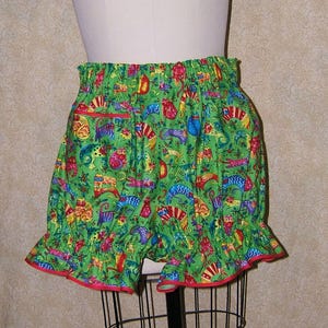 May include: Green, red, and blue patterned cotton bloomers with a red elastic waistband and a ruffled hem.
