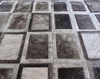 May include: A rectangular area rug constructed from individual patches of hair-on hide. The rug features a repeating grid pattern of alternating dark charcoal, medium gray, and light silver-white rectangular panels with visible stitching.
