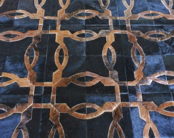 May include: A rug constructed from individual square patches of cowhide leather. The surface features a repeating geometric pattern created by alternating black and brown hair-on-hide tiles, forming interconnected oval and rectangular shapes.