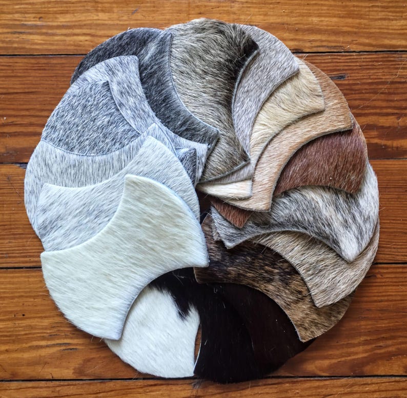A circular arrangement of various animal fur samples, including white, gray, brown, and black, displayed on a wooden surface.