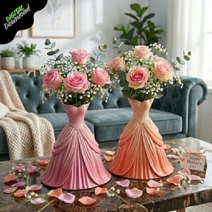 May include: Two decorative vases shaped like dresses, one pink and one peach, each holding a bouquet of pink roses and baby's breath. The vases sit on a table with scattered rose petals. A tag reads "Happy Mother's Day."