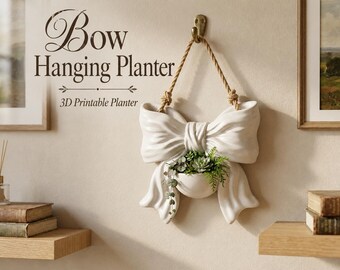 Puede incluir: Una maceta colgante blanca con forma de lazo, suspendida por una cuerda gruesa de un gancho de pared metálico. La maceta tiene un cuenco central con pequeñas suculentas verdes y follaje colgante. Texto: Bow Hanging Planter, 3D Printable Planter.