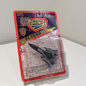 May include: A Road Champs Flyers diecast metal and plastic B-29 Superfortress airplane toy in its original red and black blister packaging. The card features a map background, the text Road Champs, and details about the B-29 Superfortress aircraft.