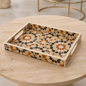 Puede incluir: Una bandeja rectangular con un patrón de mosaico geométrico en tonos crema, beige, marrón y negro. La bandeja tiene lados elevados con asas recortadas integradas en dos extremos, mostrando un diseño repetitivo de estrellas y polígonos.