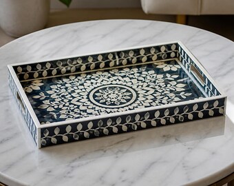 Peut inclure: Un plateau de service rectangulaire doté d'une base bleu marine foncé avec un motif floral mandala blanc complexe au centre. Les côtés du plateau sont décorés d'un motif de vigne à feuilles blanches répétitif et incluent des poignées latérales.