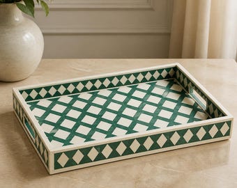 Peut inclure: Un plateau de service rectangulaire orné d'un motif répétitif en losanges vert forêt profond et blanc cassé. Le plateau présente des bords surélevés avec des poignées découpées intégrées sur les côtés courts, au design géométrique.