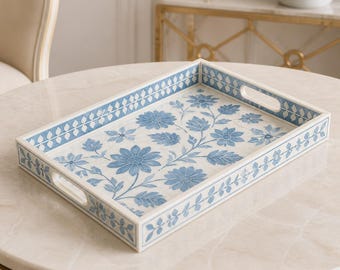 Peut inclure: Un plateau de service rectangulaire doté d'une base blanche ornée d'un motif floral bleu composé de fleurs et de feuilles. Le plateau présente des bords surélevés avec des poignées intégrées et une bordure géométrique bleue et blanche.