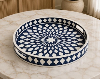 Peut inclure: Un plateau de service rond présentant une base bleu marine profond avec un motif géométrique floral blanc rayonnant depuis le centre. Le plateau possède des bords surélevés avec des poignées intégrées et une bordure en trèfle blanc.