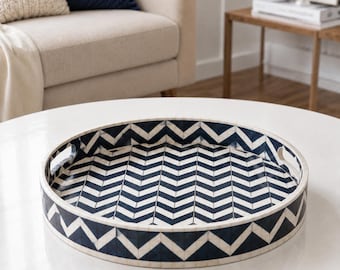 Peut inclure: Un plateau de service rond arborant un motif chevron contrasté bleu marine et blanc. Le plateau présente une finition lisse et brillante, des bords surélevés et deux poignées découpées intégrées de chaque côté pour faciliter la prise.