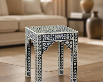 Peut inclure: Une table d'appoint carrée dotée d'une base bleu foncé avec des motifs incrustés de fleurs et de vignes blanches. La table possède quatre pieds droits avec des découpes arquées en haut et un plateau plat orné d'un motif circulaire central.