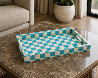 Peut inclure: Un plateau de service rectangulaire présentant un motif à damier vibrant composé de carrés alternés bleu turquoise vif et blanc cassé. Le plateau possède des bords surélevés et des poignées découpées intégrées sur les côtés courts.