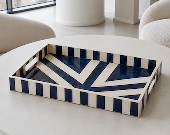 Peut inclure: Un plateau de service rectangulaire présentant un motif à rayures bleu marine et blanc crème sur les parois extérieures et un design géométrique en chevron sur la base intérieure. Le plateau comporte deux poignées découpées intégrées.