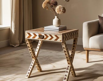 Peut inclure: Une table d'appoint carrée présentant un motif à chevrons complexe dans des tons de bois crème clair et brun foncé alternés. La table possède un tiroir unique avec une petite poignée en métal et repose sur des pieds croisés incrustés.
