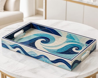 Peut inclure: Un plateau de service rectangulaire présentant un motif en mosaïque de vagues océaniques tourbillonnantes dans des tons bleu foncé, bleu clair et crème. Le plateau possède une finition lisse, un bord surélevé et deux poignées découpées.