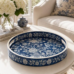 May include: A round serving tray featuring a deep blue and white floral pattern with birds and a central vase motif. The tray has a smooth, glossy finish, raised sides, and two integrated cutout handles for carrying, showcasing a classic chinoiserie design.