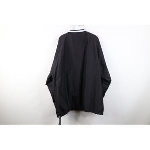 May include: Black jacket with a white and navy blue striped collar. The jacket has a drawstring at the bottom and is hanging against a white background. The jacket is a solid black color.